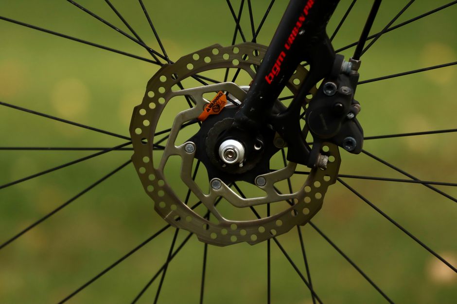 Detailed view of a bicycle disc brake on a green background.