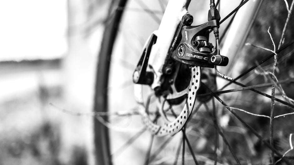 Detailed monochrome close-up of a bicycle disc brake on an outdoor ride.