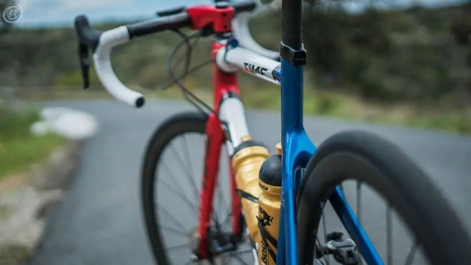 Dynamic perspective of a road bike with water bottles, focusing on vibrant frame and outdoor setting.