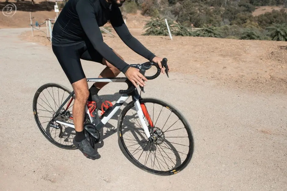 Adult male cyclist riding a road bike outdoors on a sunny day.
